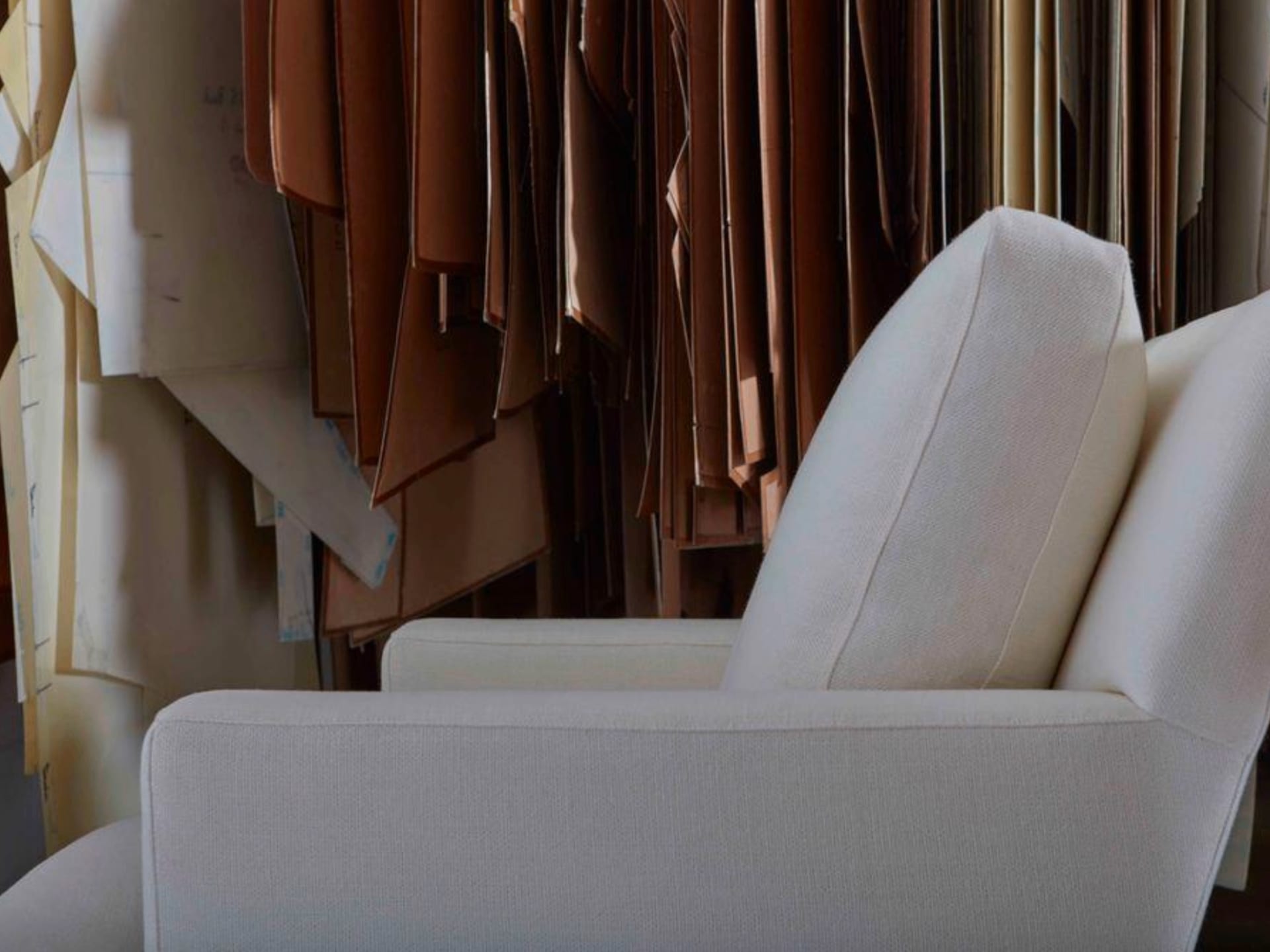 Stacked leather hides hung in the atelier behind a freshly upholstered linen chair
