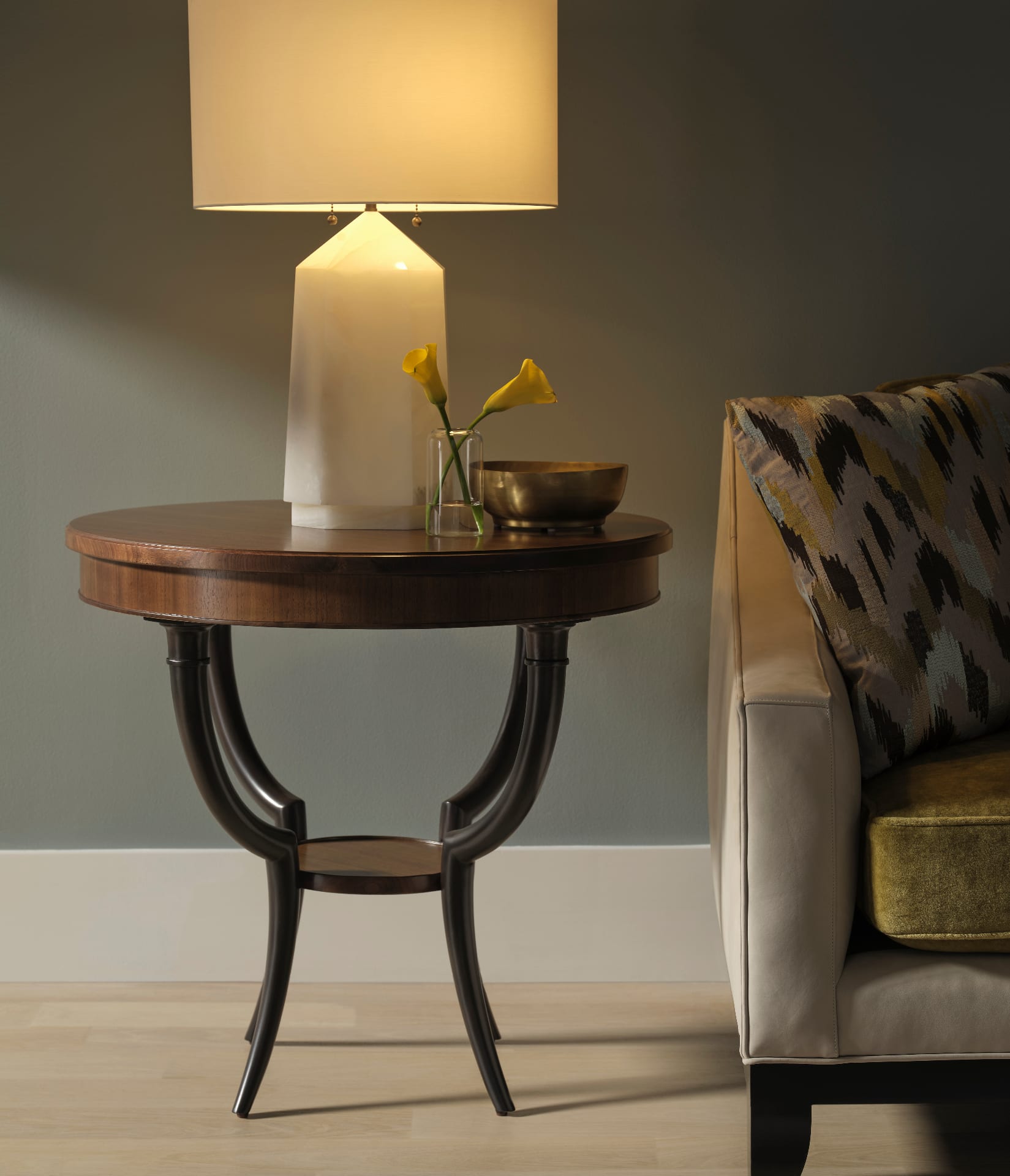 A formal Baker drawing room — tufted ivory sofa, klismos chairs, brass-edged cocktail table on a sisal rug