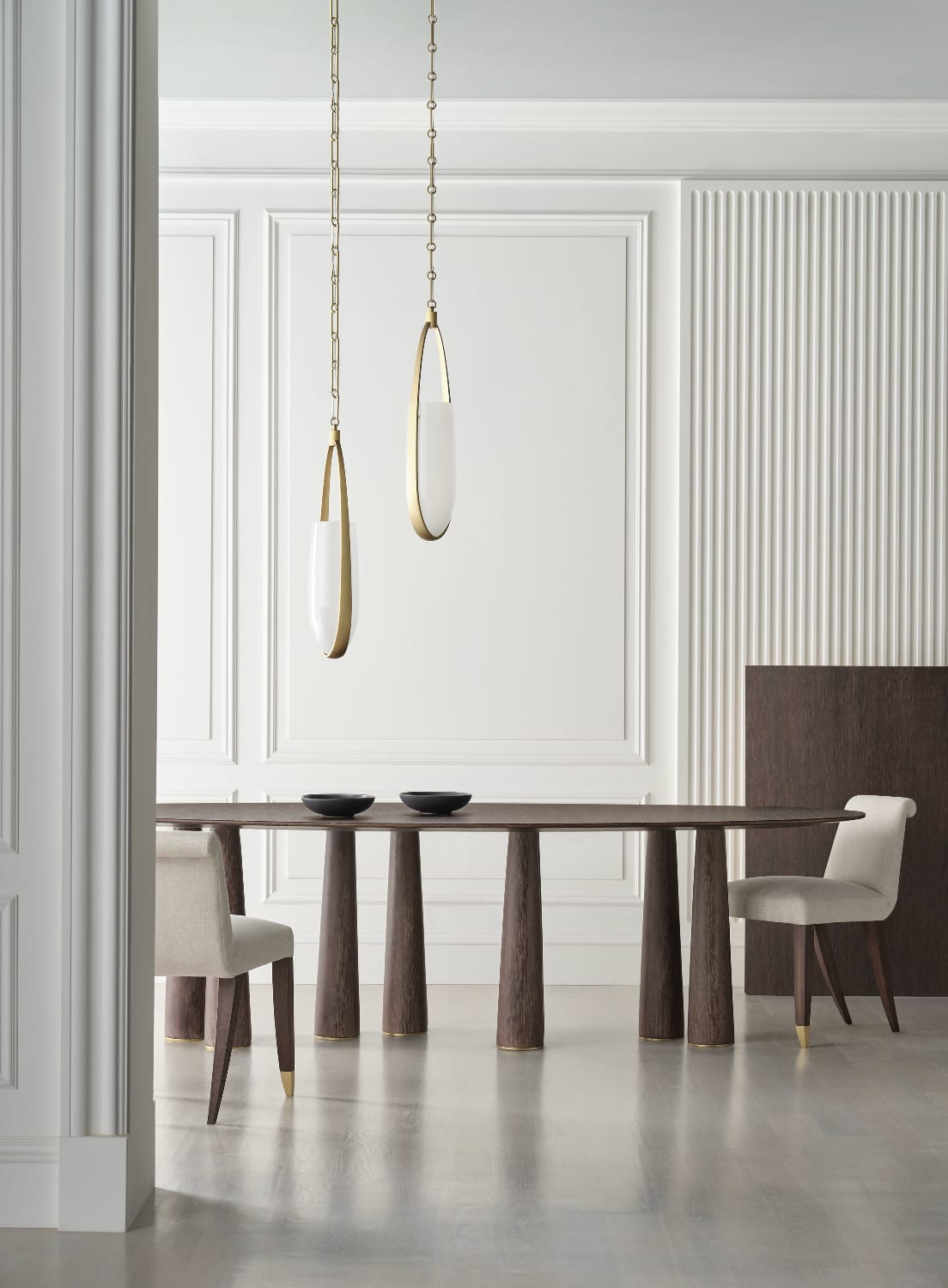 A layered American drawing room — sculpted walnut sofa, woven cane lounge chair, hand-bound rawhide pillow, late golden light through a tall arched window