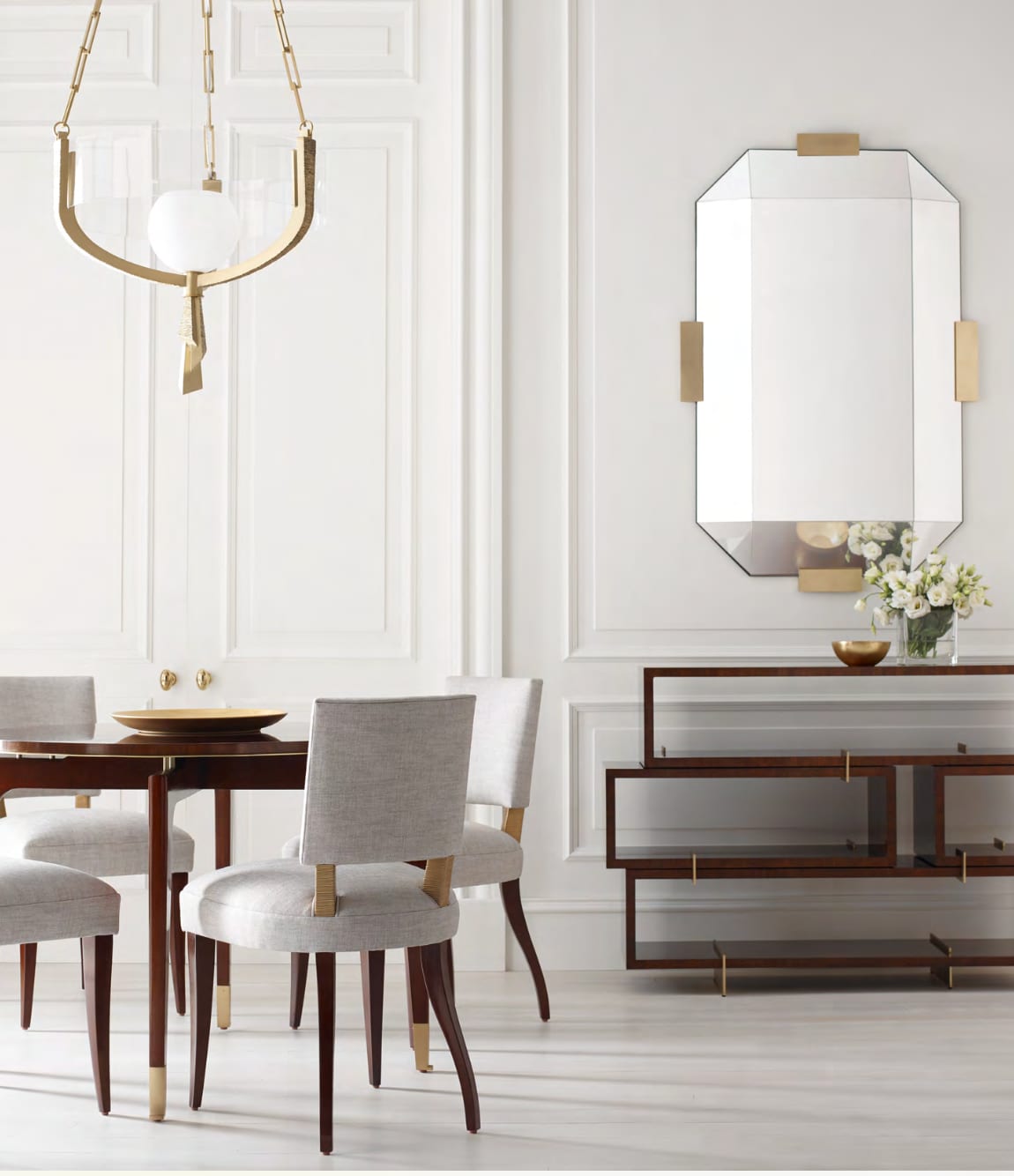 A composed dining room — walnut console, faceted brass-trimmed mirror and linen armchairs