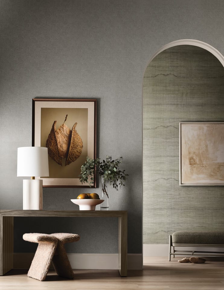 A grasscloth-walled entry with arched threshold, console and quiet artwork