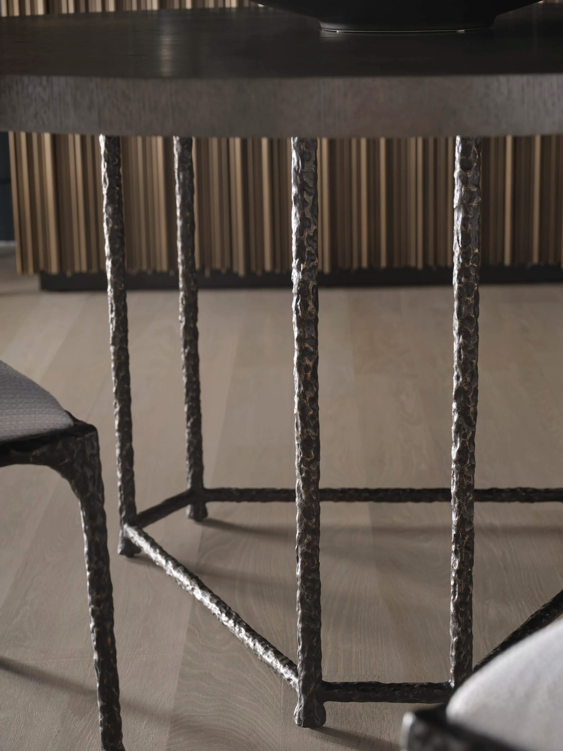 Detail — textured bronze table base on a pale timber floor