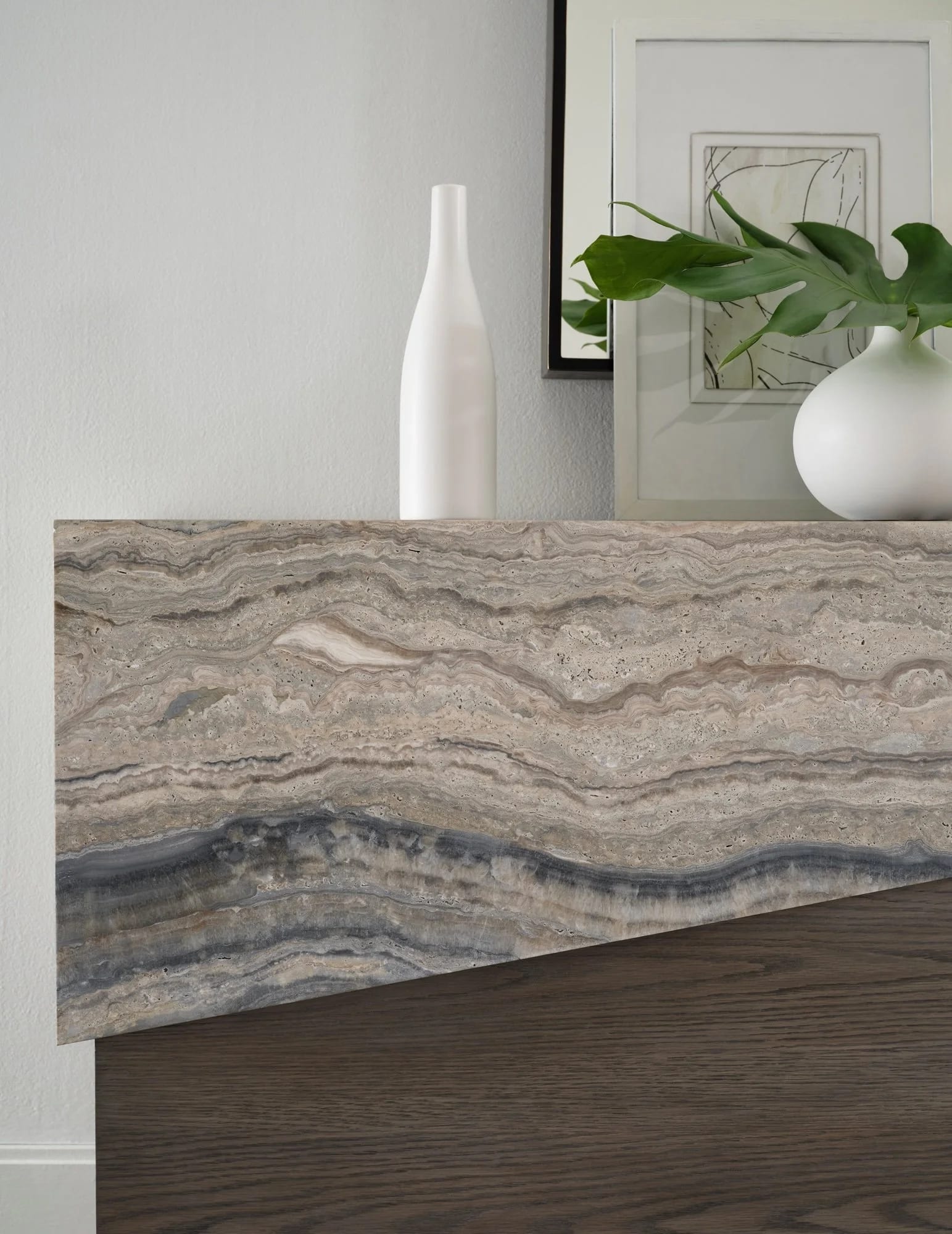 A close detail of stone, bronze and pale upholstery in a quiet interior
